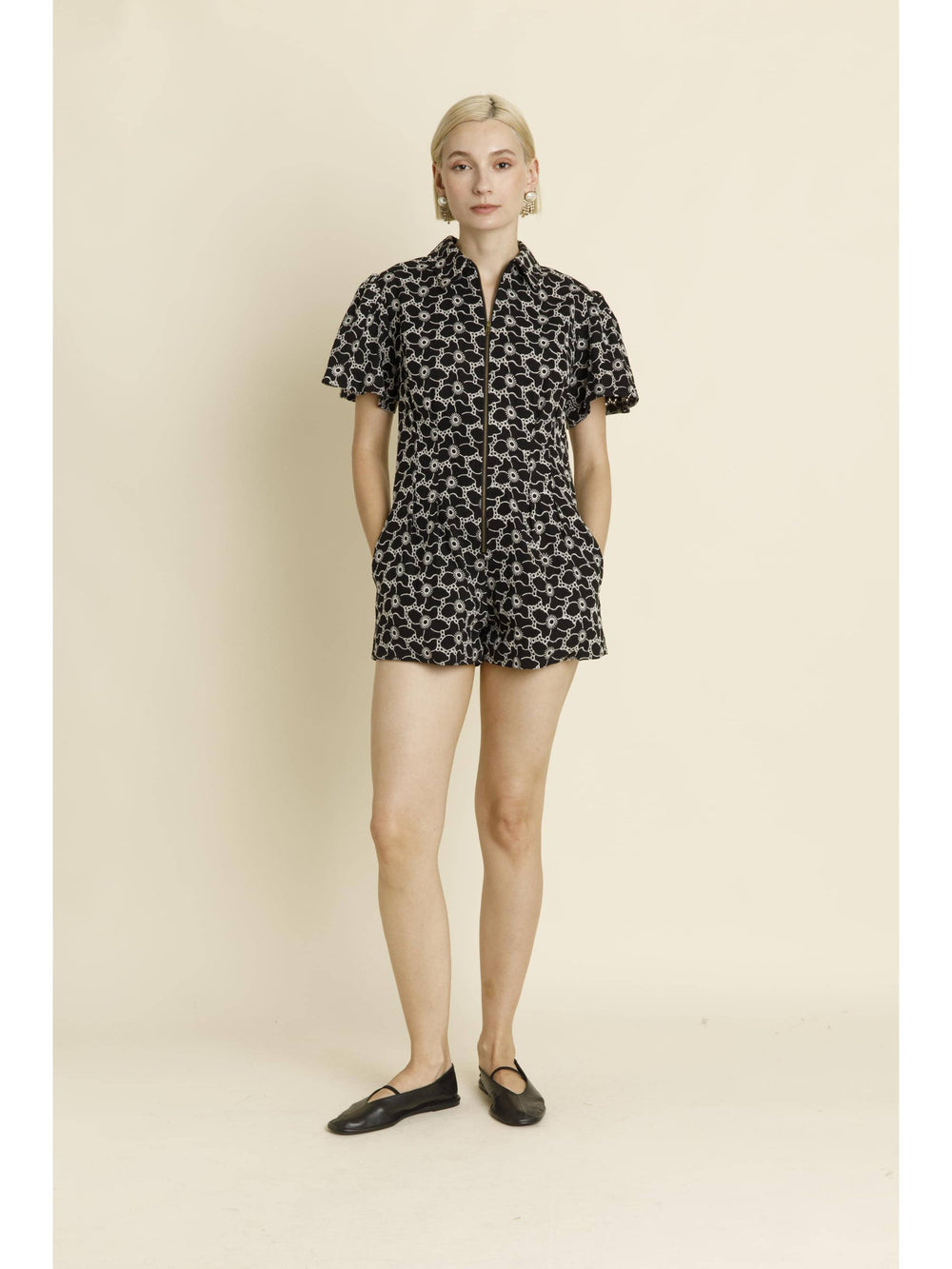 Woman wearing black floral print short-sleeve romper with button front and shorts
