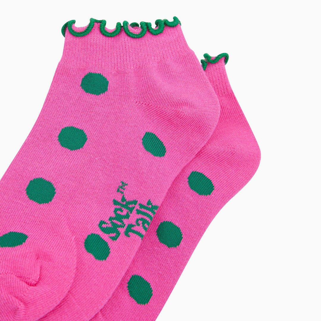 Pink trainer socks with green polka dots and green frilled cuff trim, pair shown