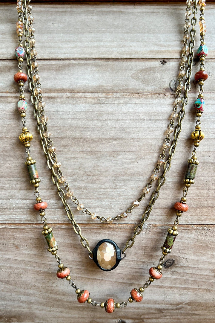 Three-strand brass chain necklace with multicolor beads and oval faceted center stone