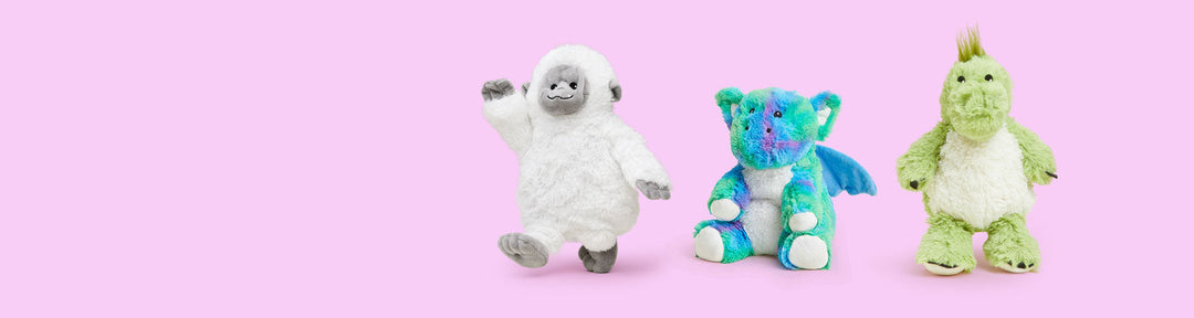 Three Warmies plush toys including white yeti, blue dragon, and green dinosaur