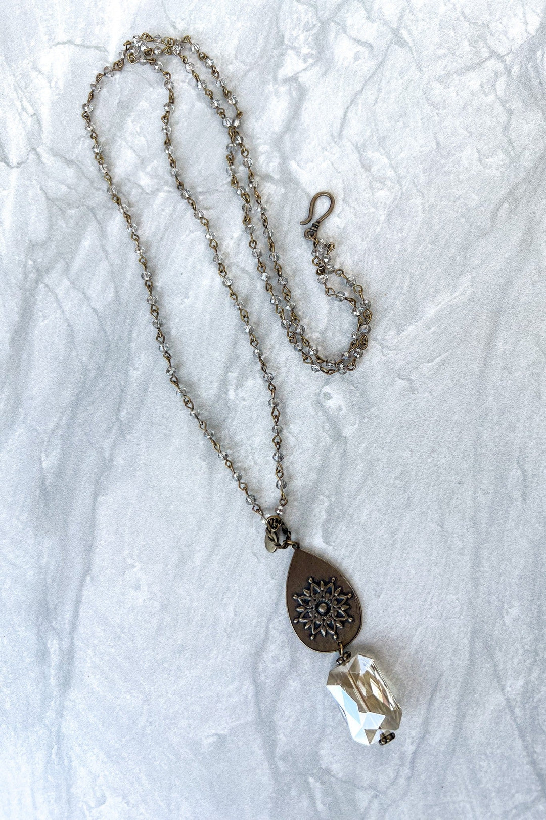 Bronze necklace with beaded chain, teardrop medallion, and faceted clear crystal pendant