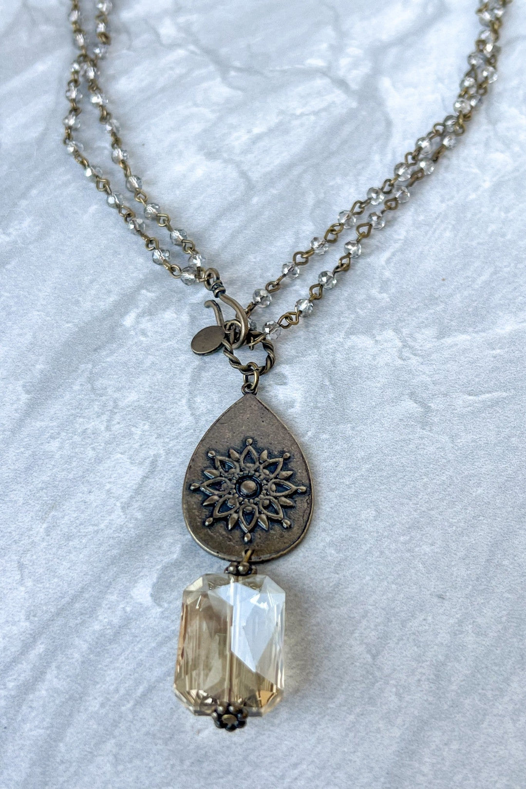 Bronze layered necklace with mandala teardrop charm and faceted champagne crystal pendant