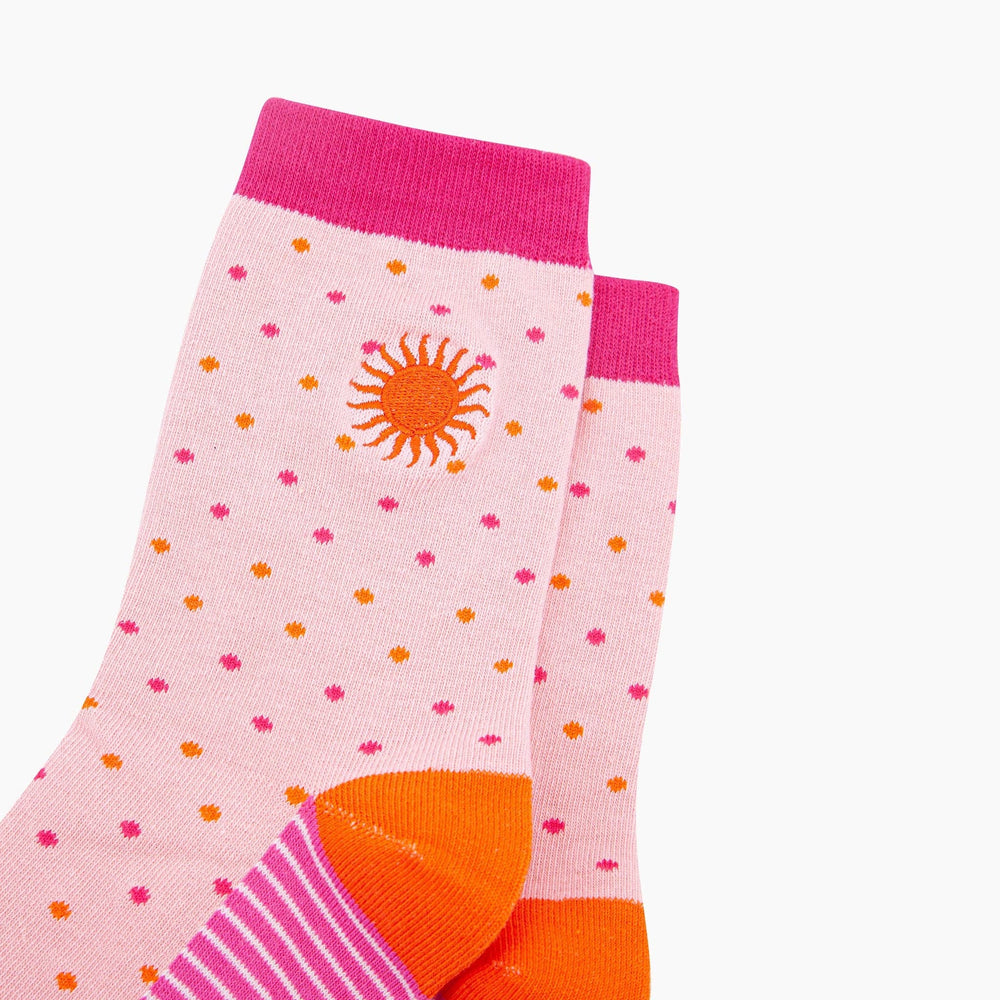 Pink crew socks with orange sun embroidery, polka dots, hot pink cuff, and orange heel