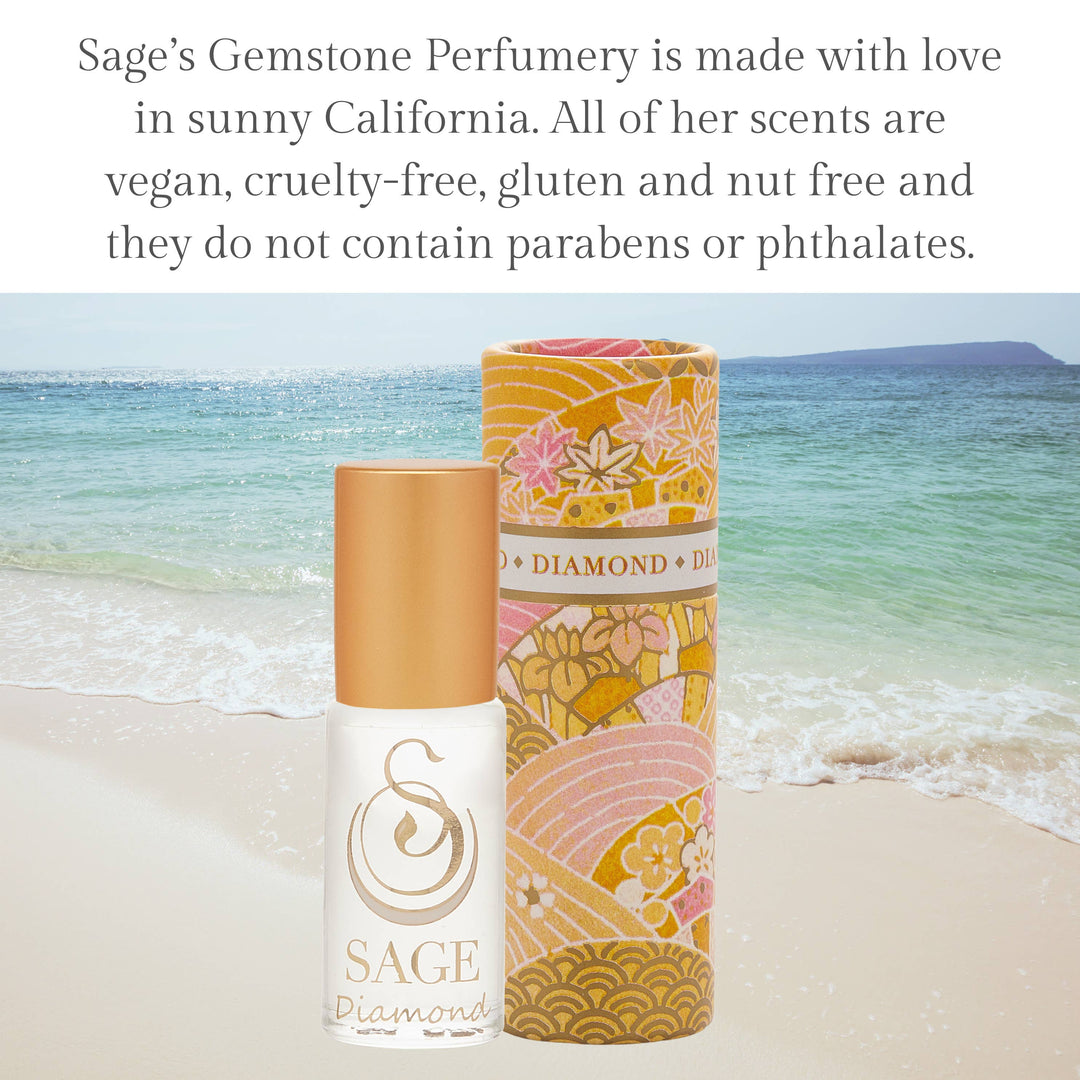 Sage Diamond perfume roller with decorative gold and pink floral tube on beach background
