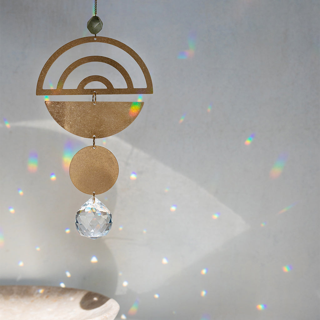 Scout Moon Phase suncatcher with bronze geometric shapes and crystal prism creating rainbow light reflections