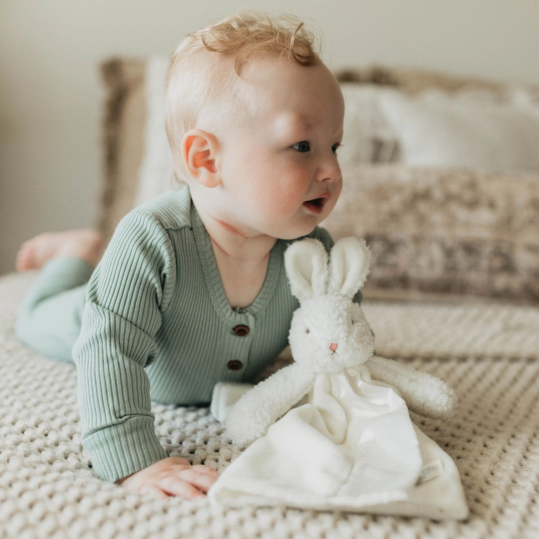 Baby holding a white plush bunny lovey security blanket by Bunnies By the Bay