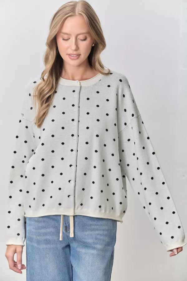 Polka dot button-up cardigan in ivory with black dots, worn with blue jeans