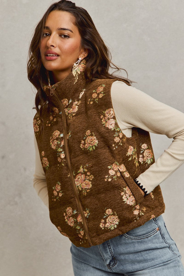 Woman wearing brown floral quilted vest over cream long-sleeve shirt with jeans