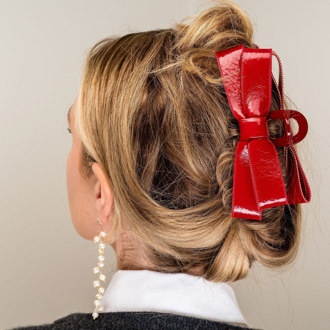 Red patent leather bow hair clip worn in blonde updo hairstyle