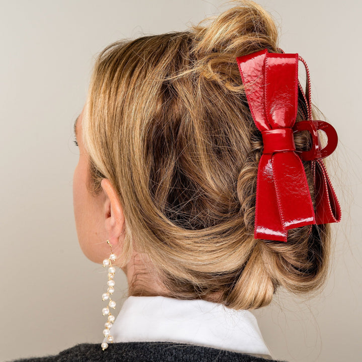 Red patent leather bow hair clip worn in blonde updo hairstyle