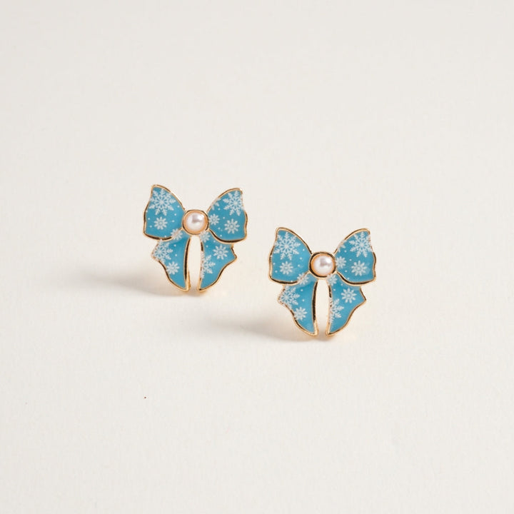 Blue snowflake ribbon bow stud earrings with pearl center and gold trim, pair shown