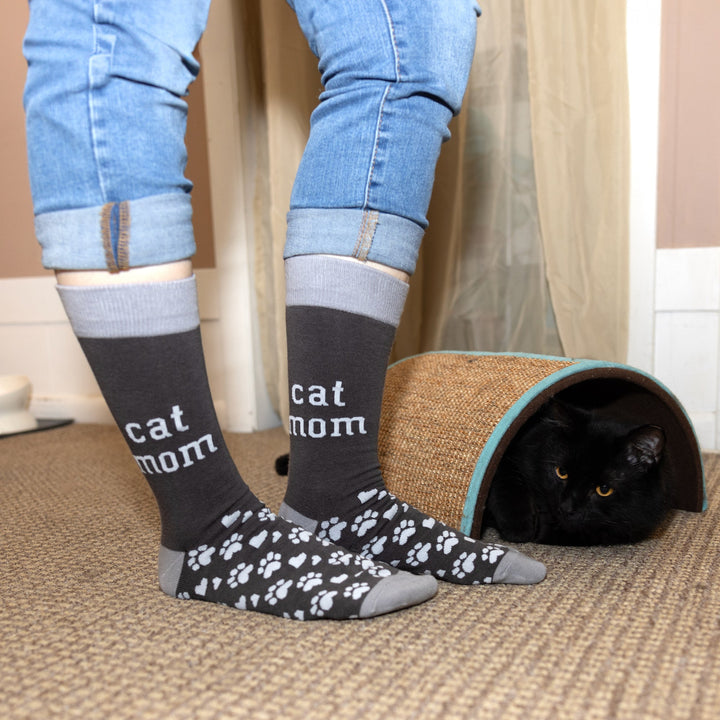 Gray crew socks with 'cat mom' text and paw prints, modeled with black cat nearby