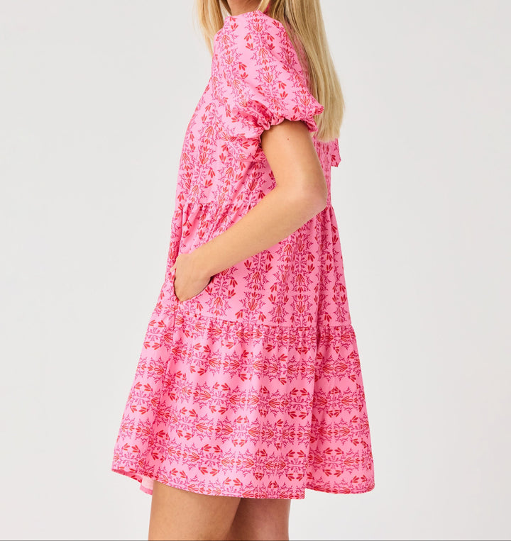 Woman wearing pink floral mini dress with short sleeves and tiered design