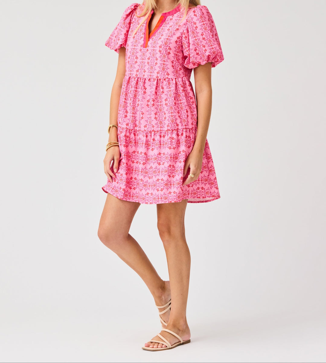 Woman wearing pink floral mini dress with puff sleeves and tiered skirt