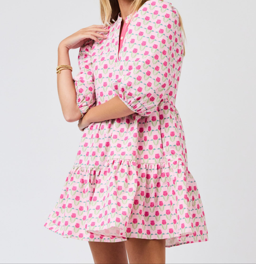 Woman wearing pink floral mini dress with ruffled hem and three-quarter sleeves