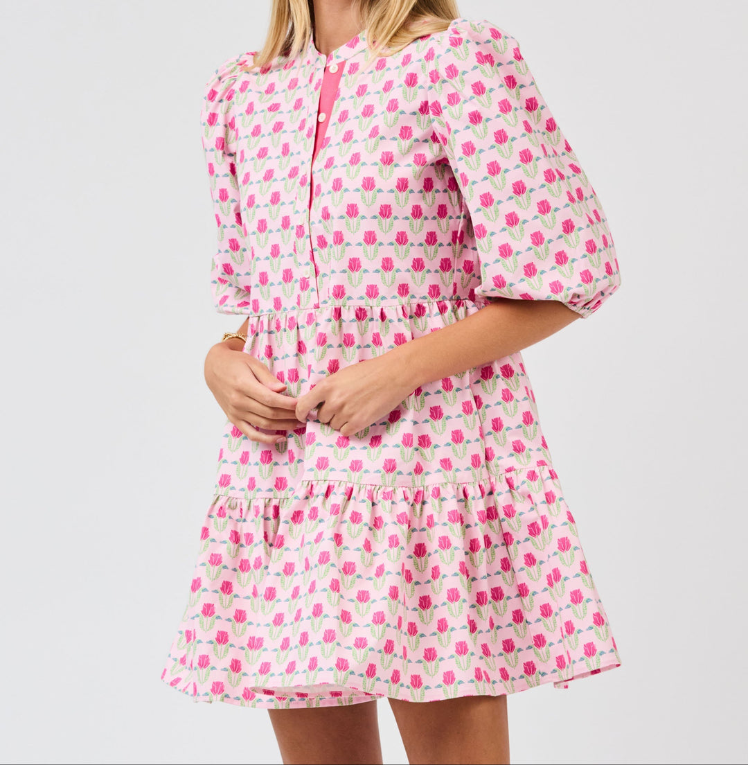 Woman wearing pink floral mini dress with puffy sleeves and tiered ruffle hem