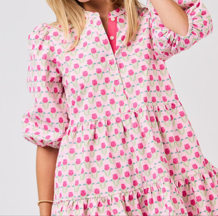 Woman wearing pink floral mini dress with puffy sleeves and tiered ruffle hem