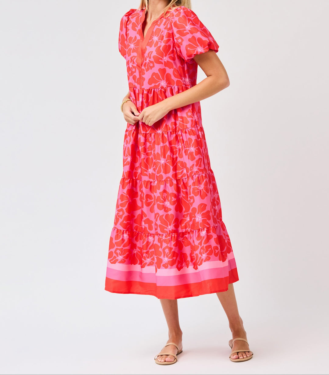 Woman wearing pink floral midi dress with tiered ruffle design and short sleeves