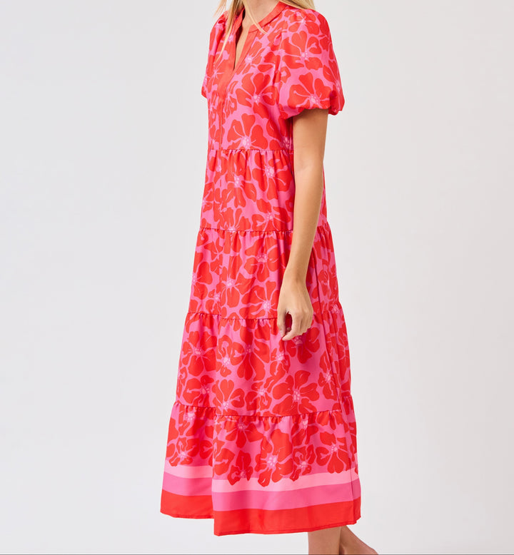 Woman wearing pink floral tiered midi dress with short sleeves and striped hem