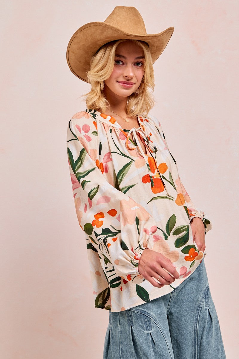 Woman wearing floral print balloon sleeve top with pink and orange flowers on white background