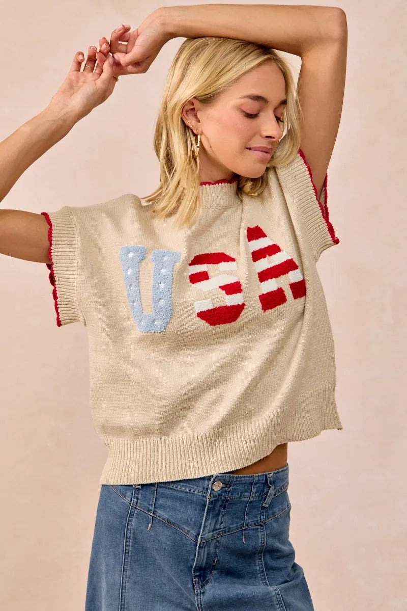 Woman wearing oatmeal colored USA patchwork sweater vest with patriotic lettering design