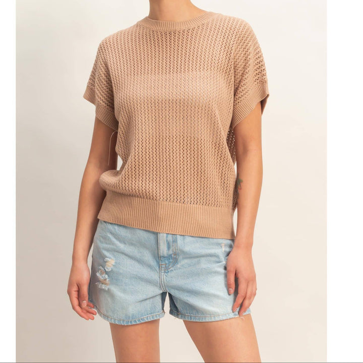 Model wearing beige open-knit short sleeve sweater top with denim shorts