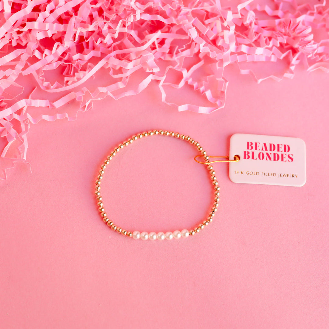 Beaded Blondes Sophia Pearl Bracelet featuring 14K gold filled beads and white pearls on pink background.