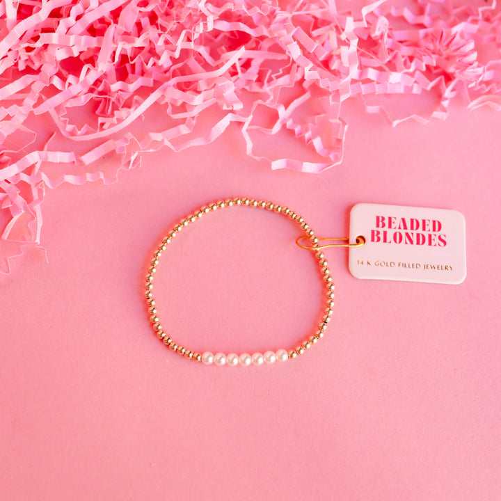 Beaded Blondes Sophia Pearl Bracelet featuring 14K gold filled beads and white pearls on pink background.