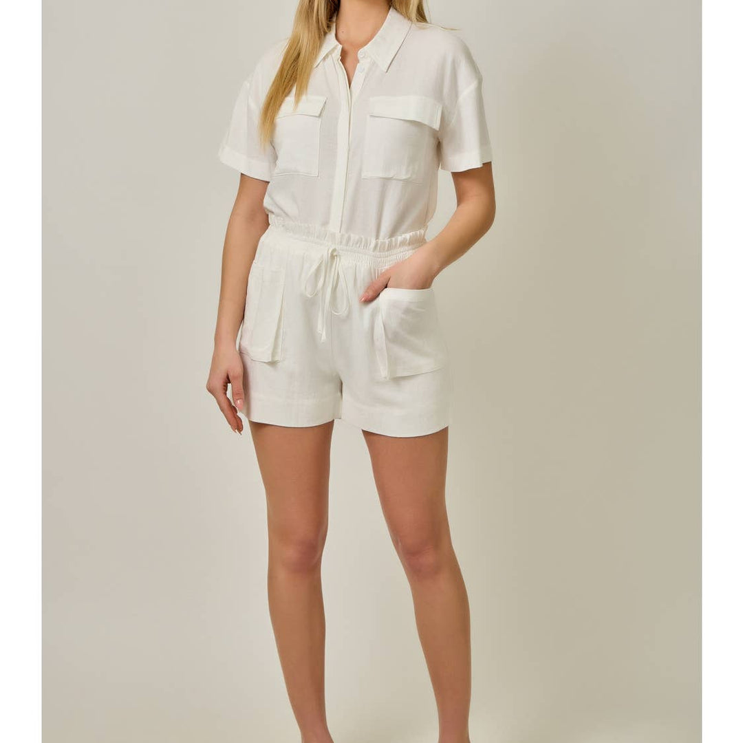 Woman wearing cream linen romper with front pockets and drawstring waist