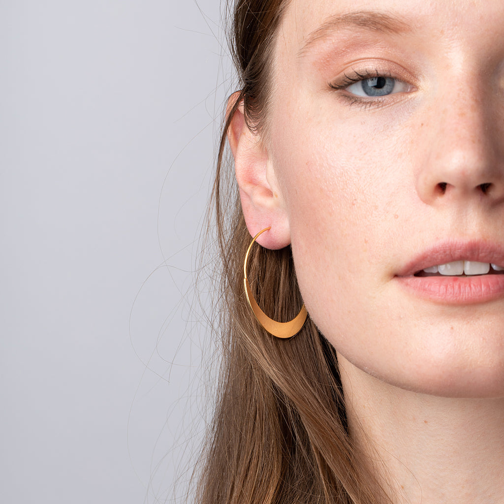Model wearing Scout Refined Collection large gold vermeil crescent hoop earring on ear