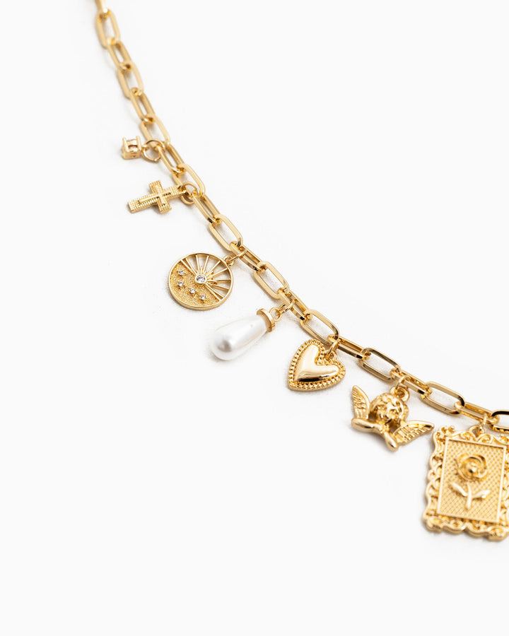 Gold charm necklace featuring cross, sun medallion, pearl, heart, angel, and framed rose pendants
