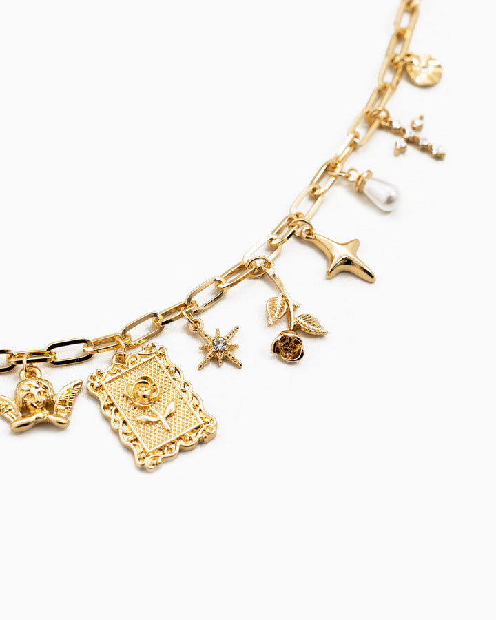 Gold multi-charm necklace featuring framed rose pendant, star, angel, pearl, and floral charms.