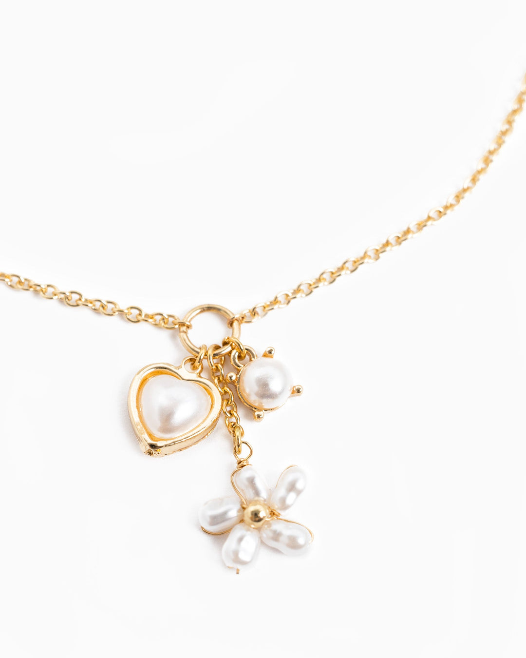 Gold Y-drop necklace with pearl heart charm, single pearl, and pearl flower pendant