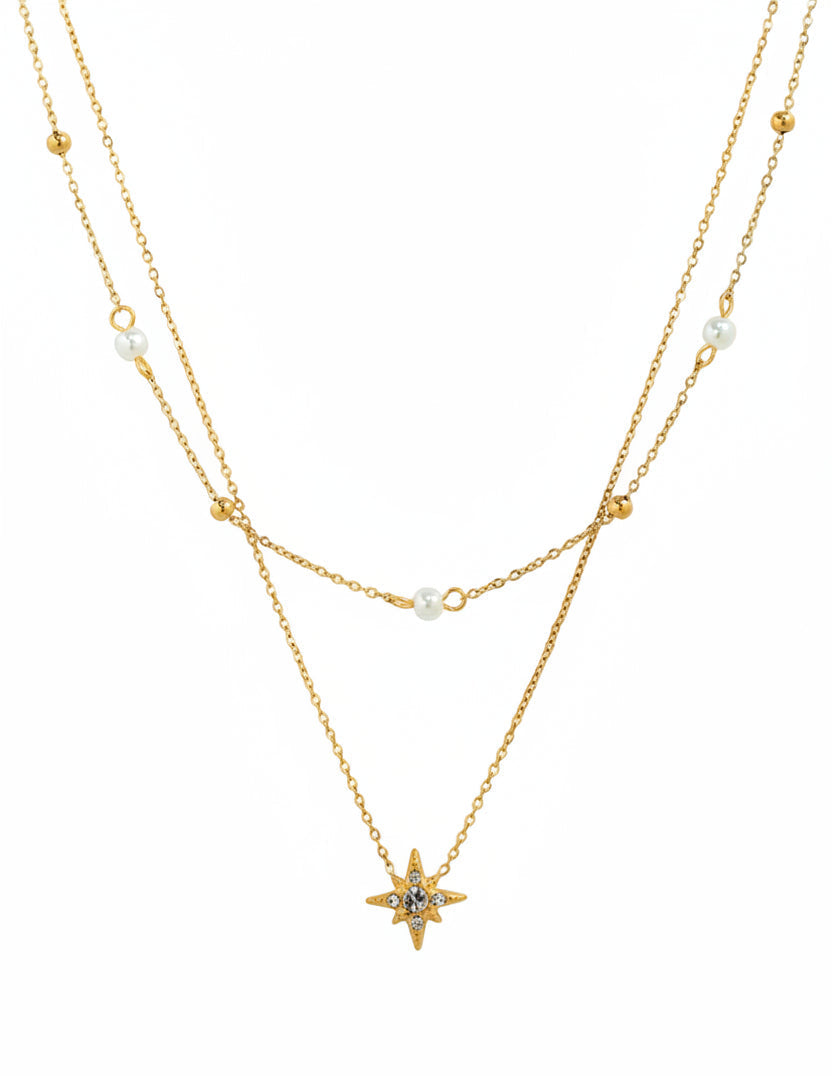 Gold layered double chain necklace featuring starburst crystal pendant and pearl accents