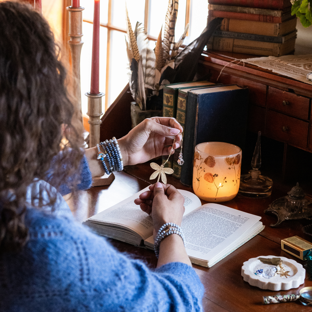 Woman holding Scout Butterfly Bookmark and Keychain Set over an open book at a desk