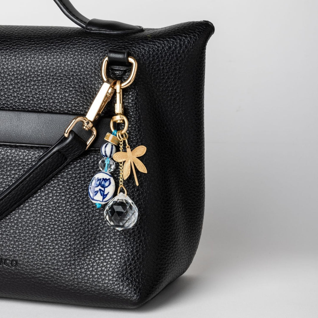 Scout Bookmark and Keychain Set with butterfly charm, blue floral bead, and crystal pendant attached to black handbag