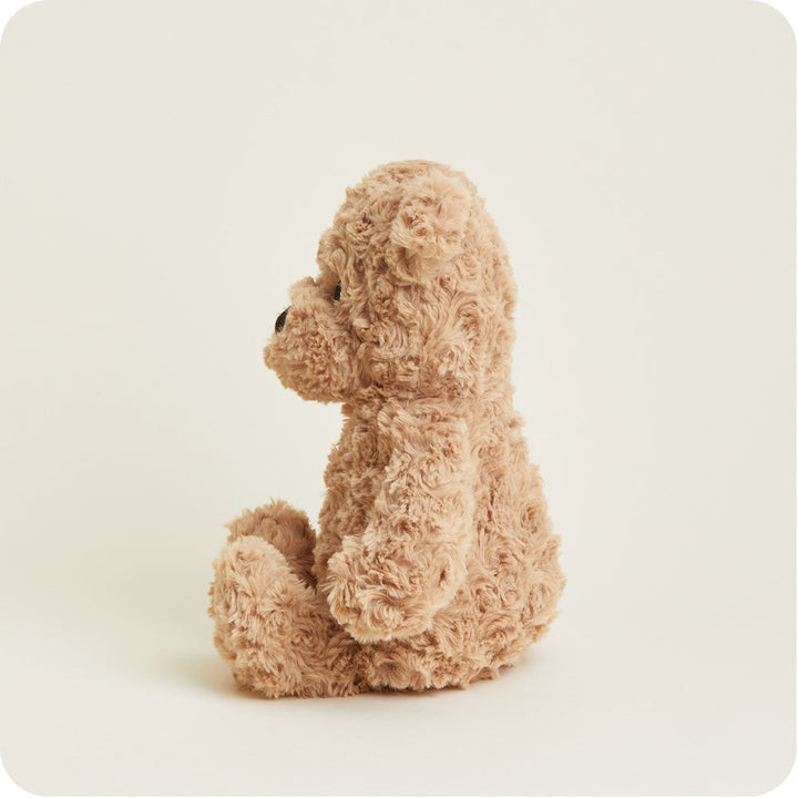 Warmies brown curly plush bear sitting against clean white background