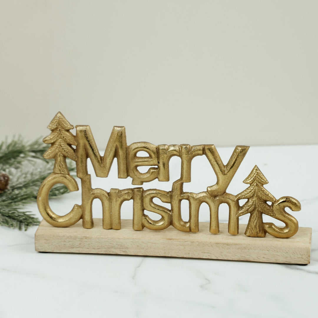 Gold Merry Christmas tabletop decoration with Christmas tree accents on wooden base