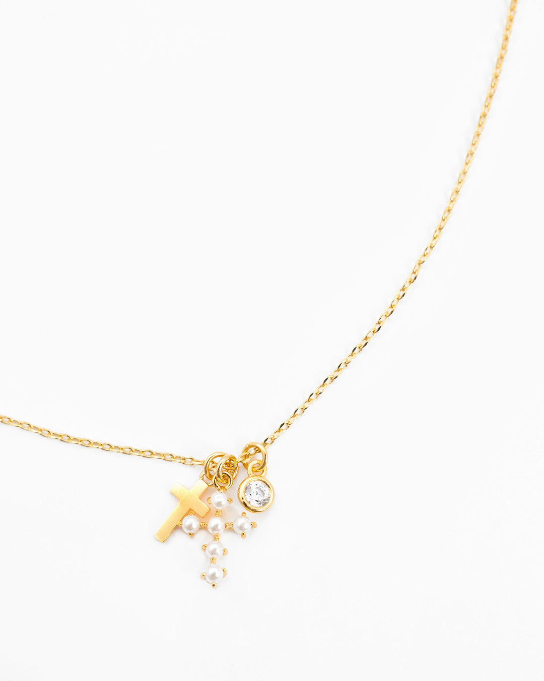 Gold chain necklace with pearl cross charm, crystal pendant, and mini pearl cluster