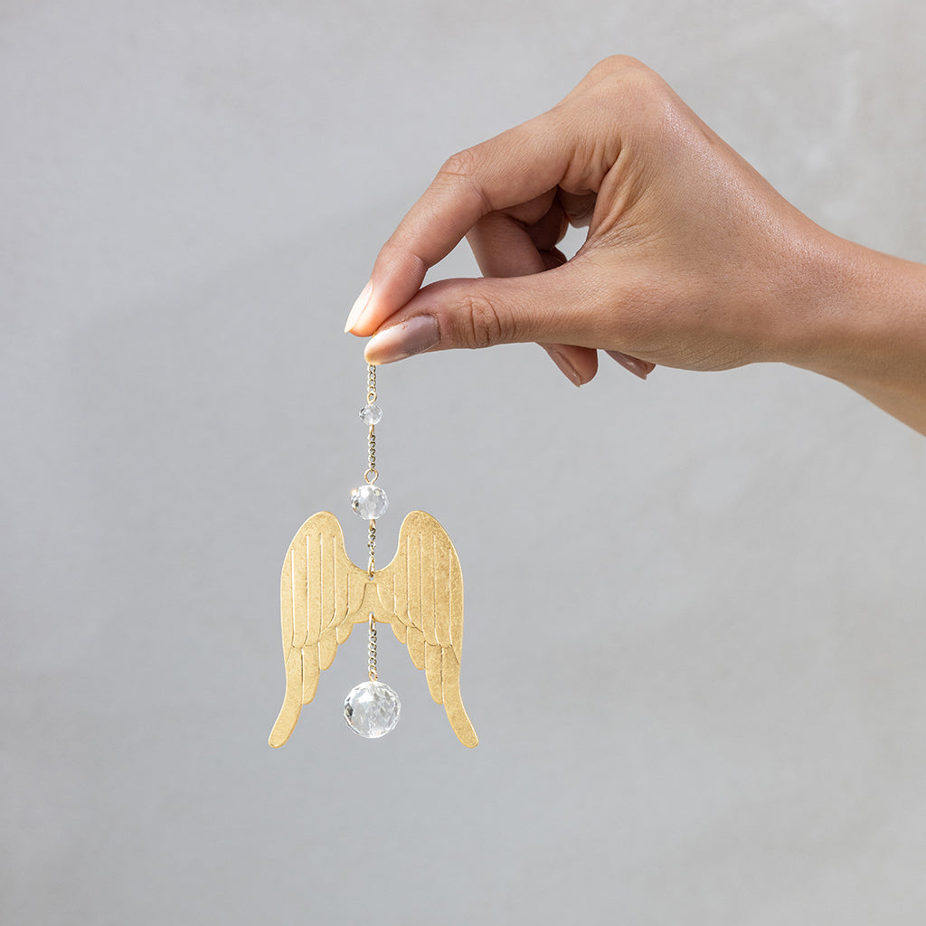 Hand holding Scout Mini Suncatcher with gold angel wings and crystal beads