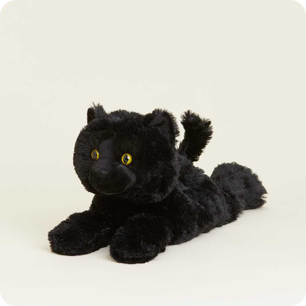 Warmies black cat plush toy with yellow eyes lying down against white background