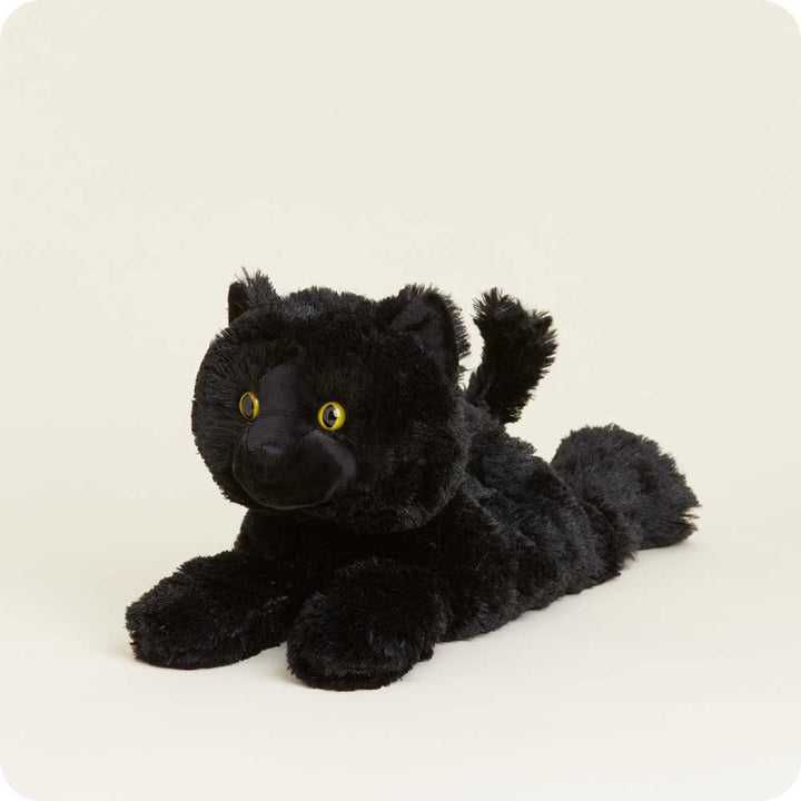 Warmies black cat plush toy with yellow eyes lying down against white background
