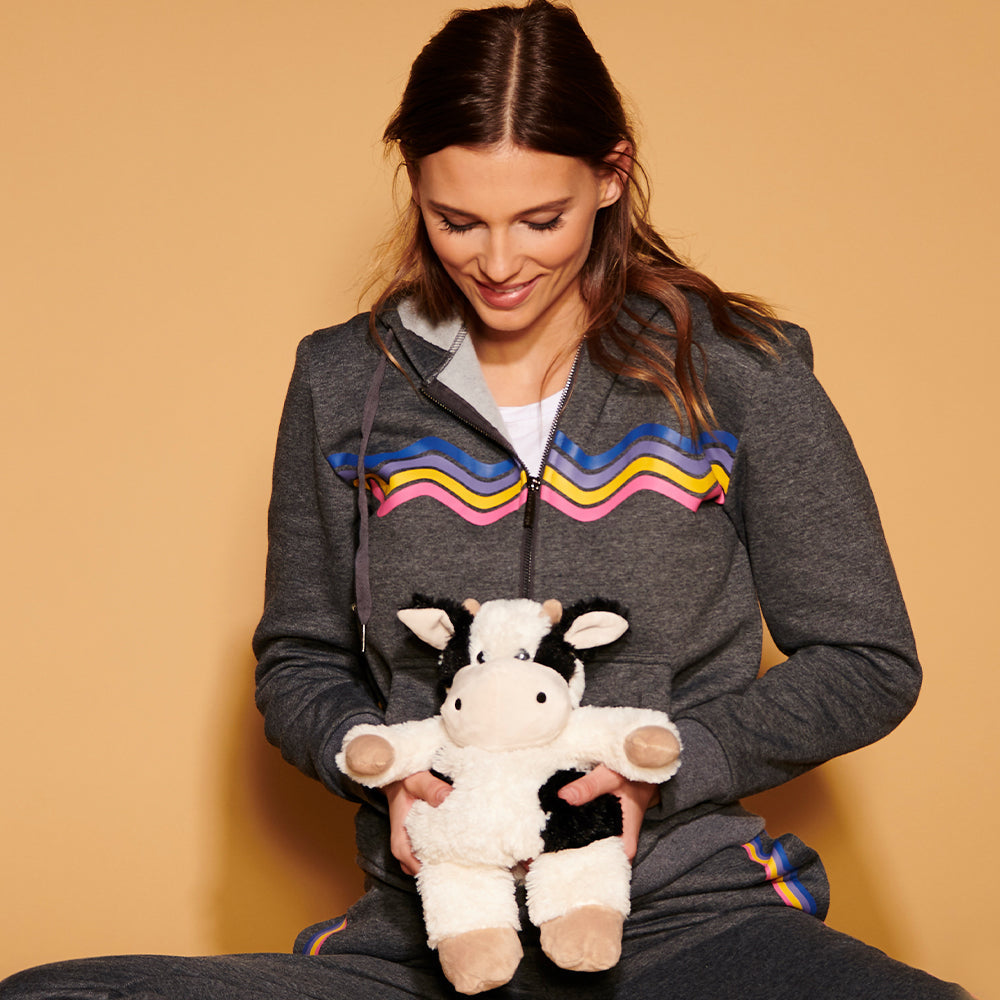 Woman holding Warmies cow plush toy with black and white spotted pattern