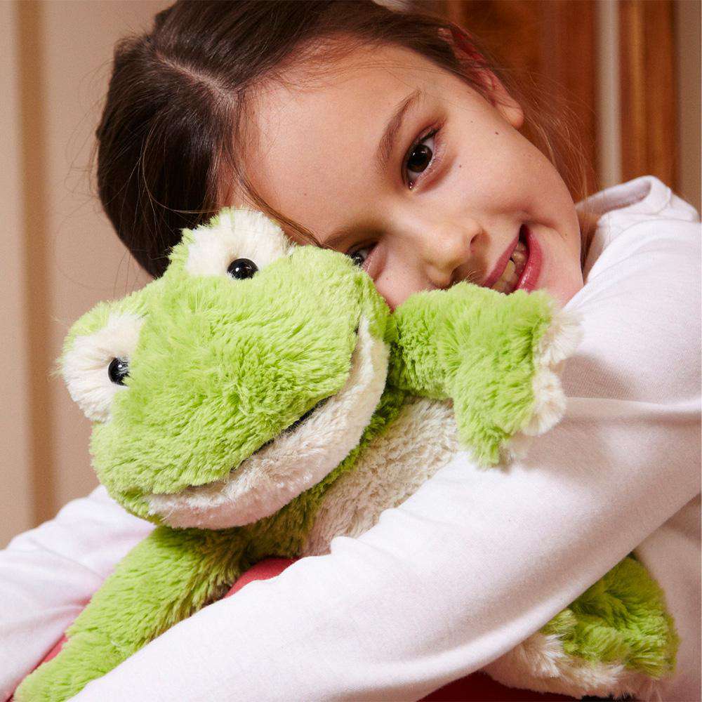 Young girl hugging green frog Warmies stuffed animal toy with white cream belly