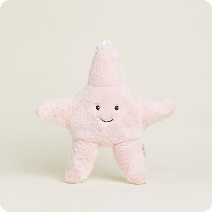 Pink fuzzy starfish-shaped Warmies plush toy with smiling face on white background
