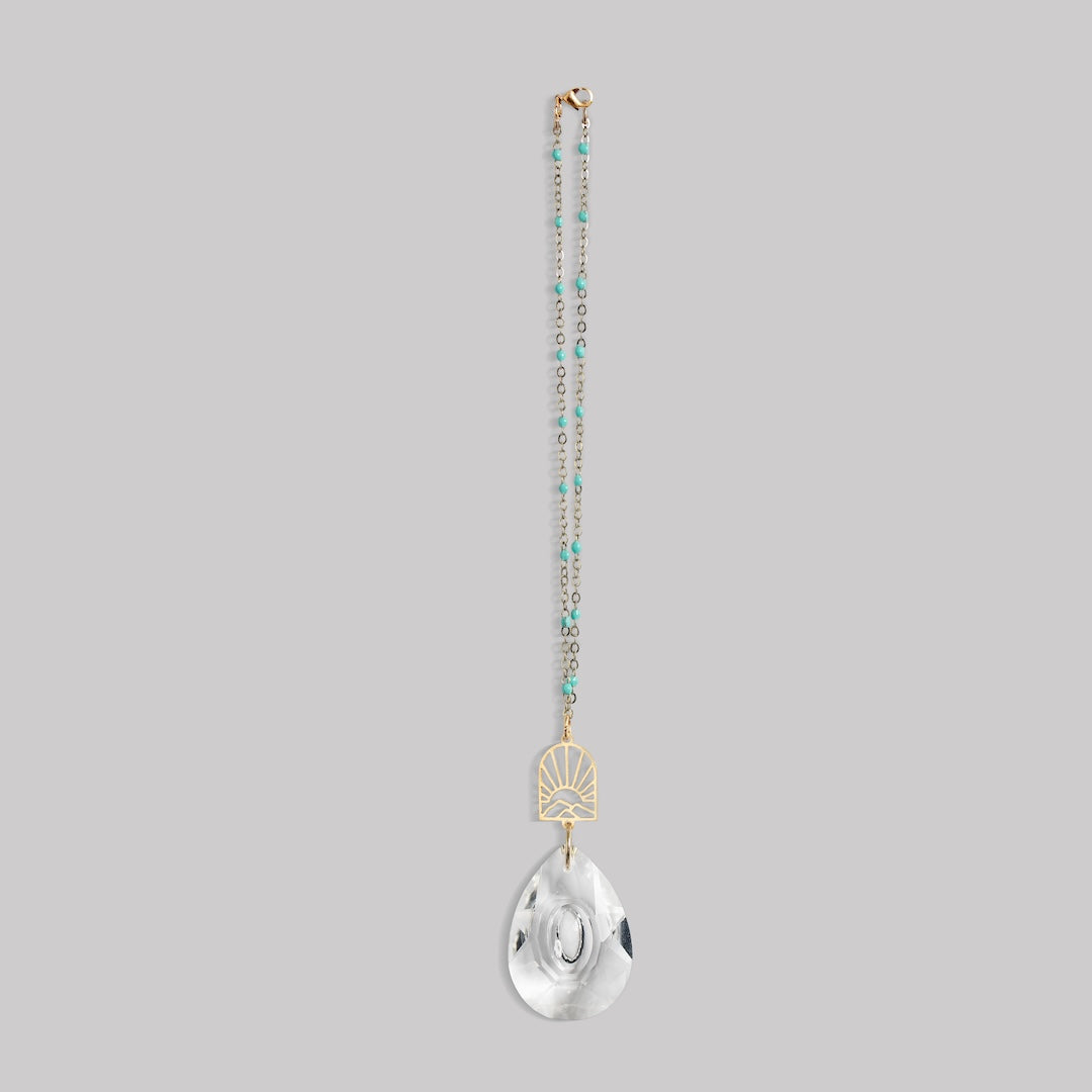 Scout Pocket Suncatcher with turquoise beaded chain, gold sunrise mountain charm, and clear crystal pendant