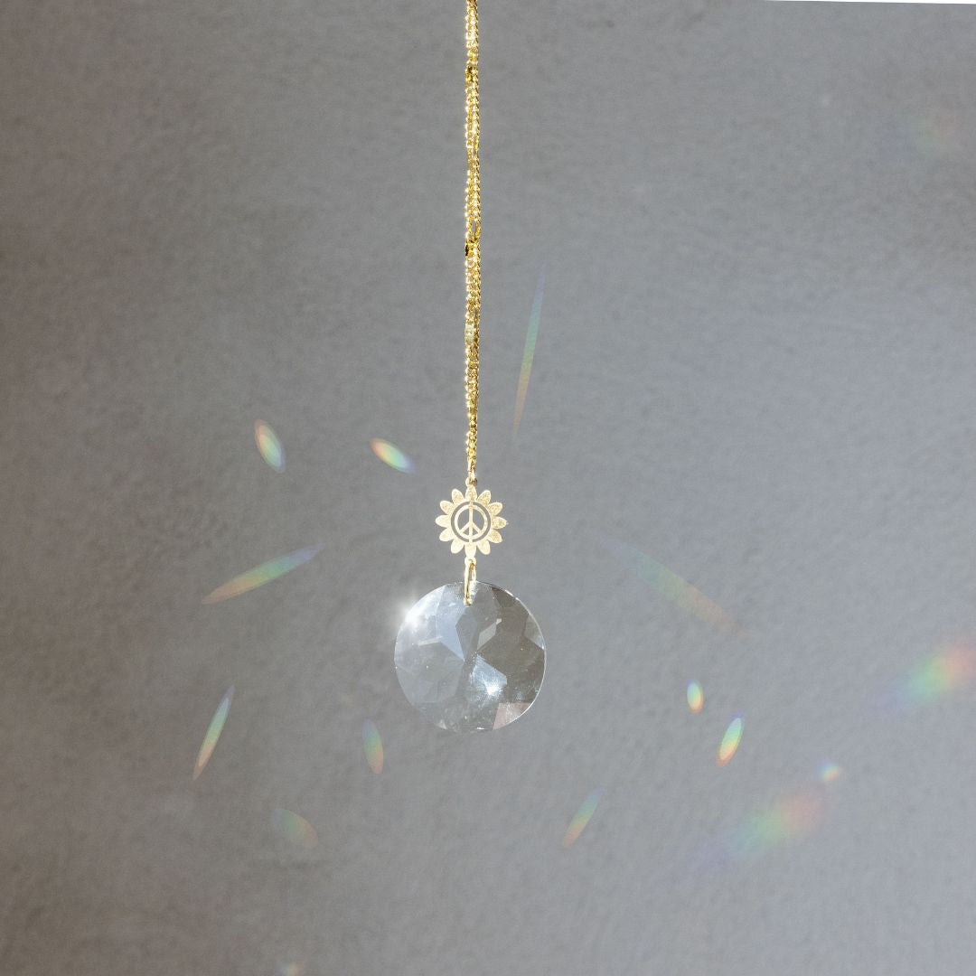 Scout Pocket Suncatcher with gold peace flower charm and clear crystal creating rainbow prisms