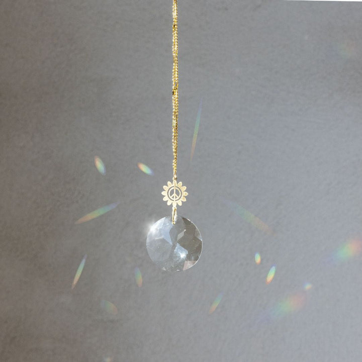 Scout Pocket Suncatcher with gold peace flower charm and clear crystal creating rainbow prisms