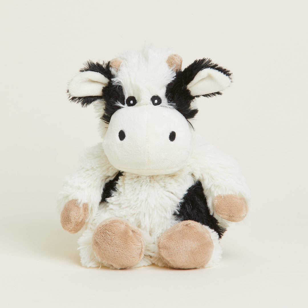 Warmies Junior black and white cow plush toy with pink hooves on white background