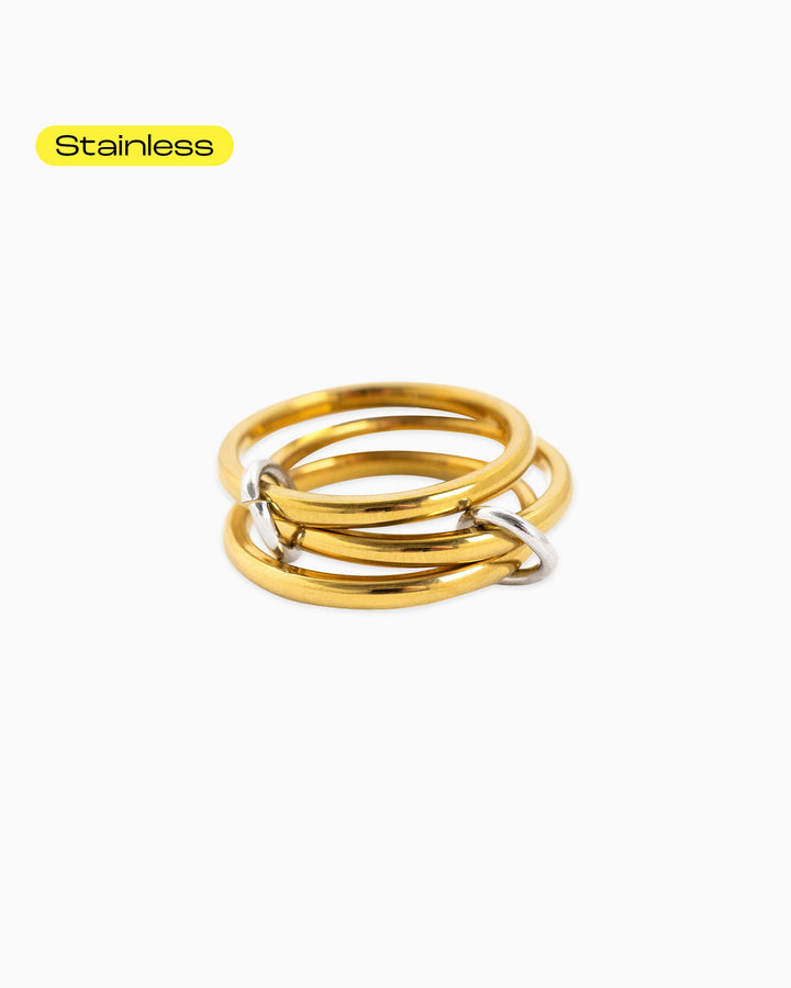 Sessori Interlocking Ring Stack featuring three gold stainless steel bands linked by a silver connector ring.